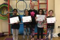 Big Buds proudly showing their Grade Two and Grade Three certificates and button badges after achieving the grades in the Blossom Yoga Syllabus