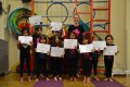 Lil' Buds proudly showing their Grade One, Grade Two, Grade Three and Grade Five certificates and badges after achieving the grades in the Blossom Yoga Syllabus